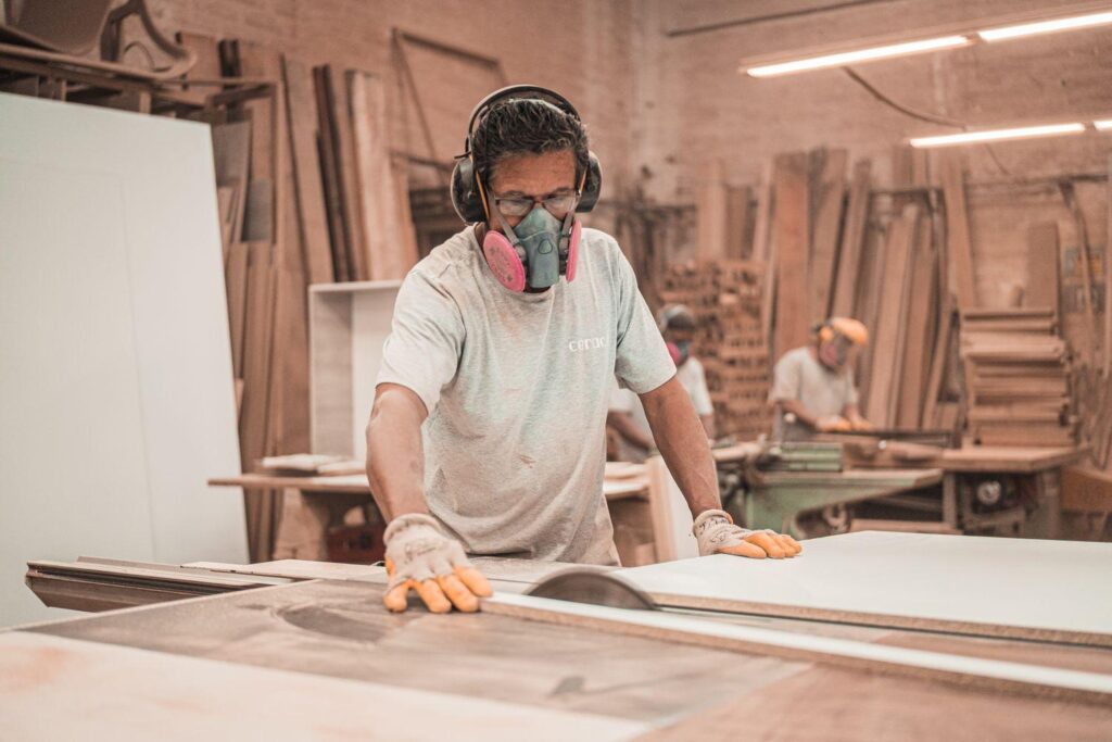 Man wearing mask working on wood cutting.